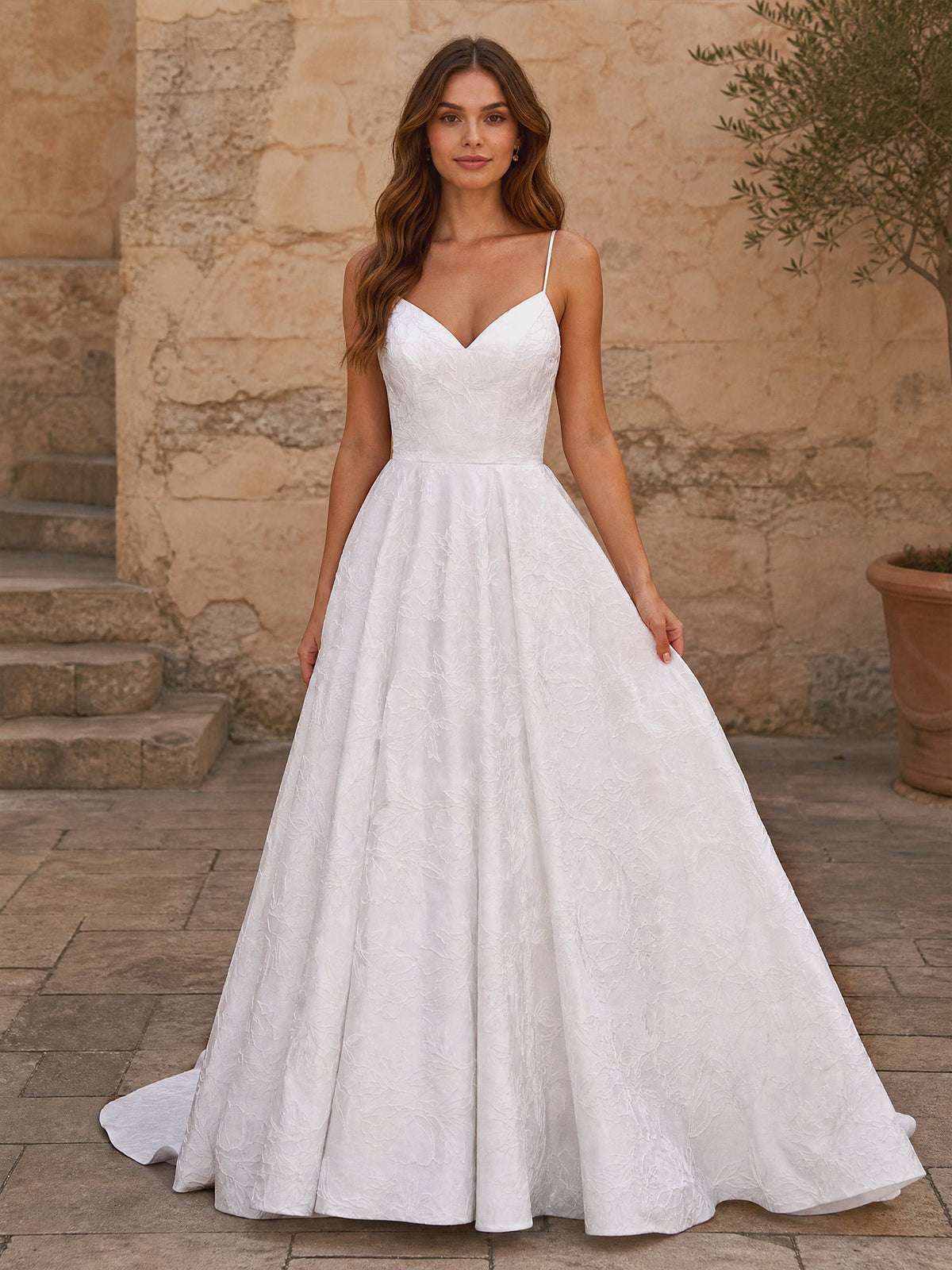 Front view of a white A-line wedding dress with a sweetheart neckline, spaghetti straps, and floral lace details.