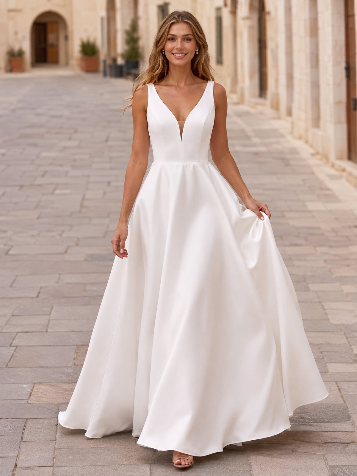 White sleeveless V-neck satin A-line gown with a full floor-length skirt, shown outdoors in front view
